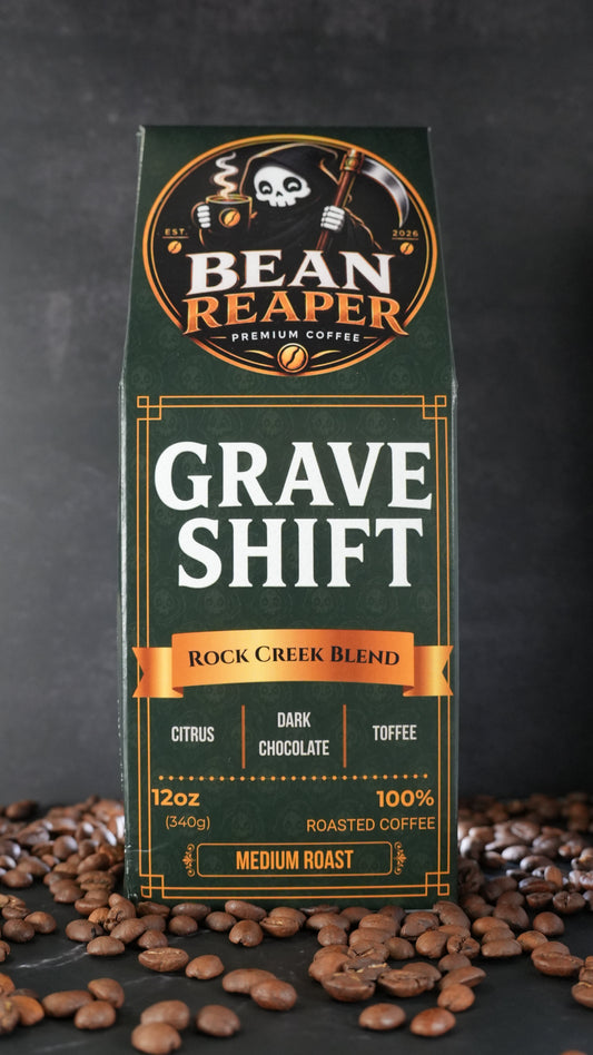 Bean Reaper Grave Shift coffee bag front — Rock Creek Blend, 12 oz medium roast, standing on whole coffee beans