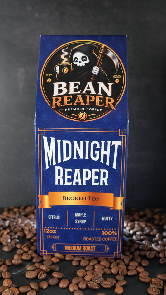 Bean Reaper Midnight Reaper coffee bag front — Broken Top blend, 12 oz medium roast, standing on whole coffee beans